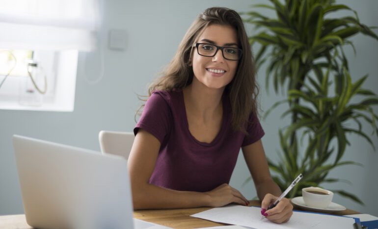 Woman with glasses smiling and taking notes