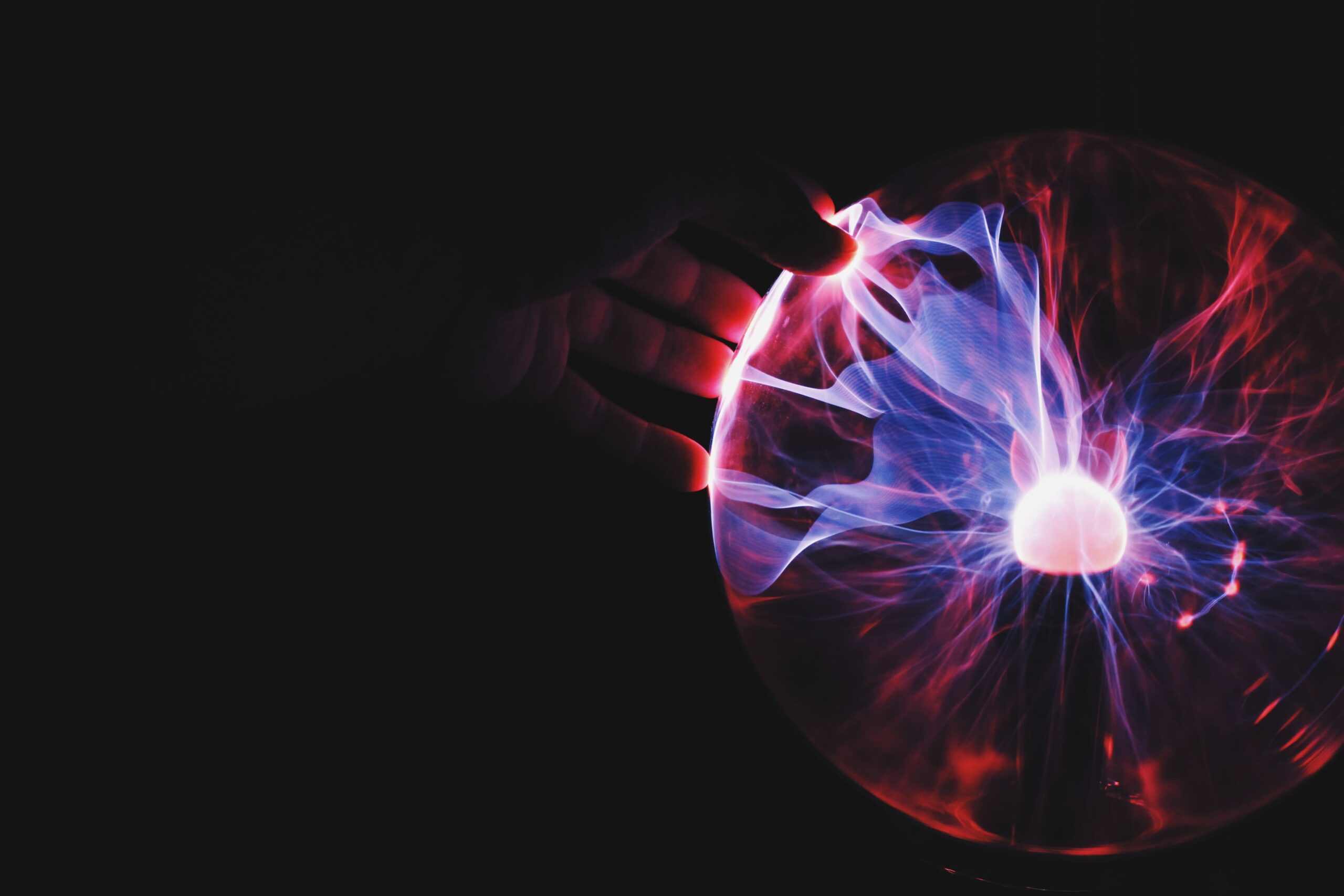 A hand touching a plasma ball