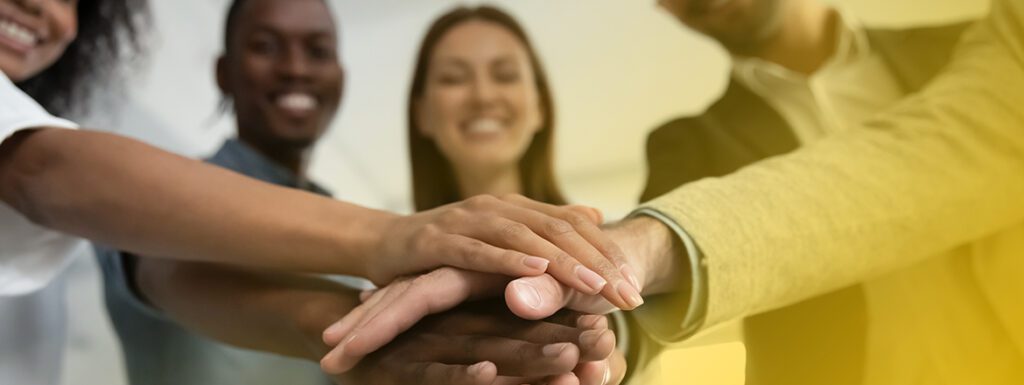Featured image for article titled "Why Employee Sustainability Training Matters for Business Success" showing a group of people putting their hands on top of each other.