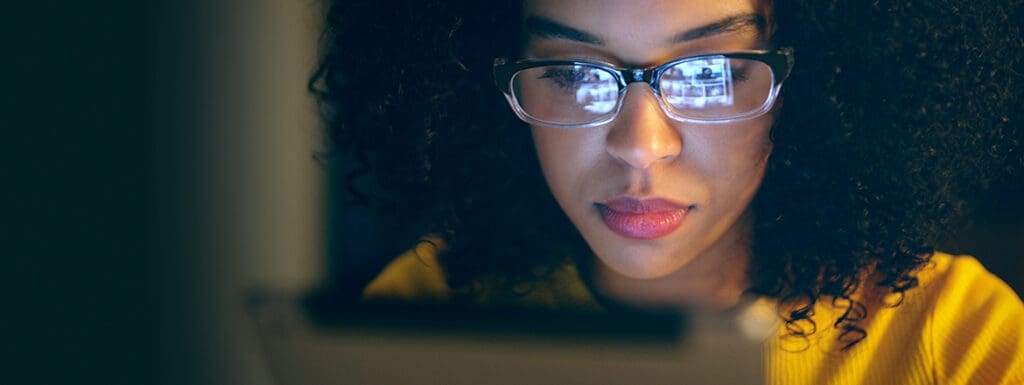 Featured image for article titled "Why is Digital Literacy Important for Continuous Enterprise Growth" showing a close up of a woman's face with a reflection of the tablet in her glasses.