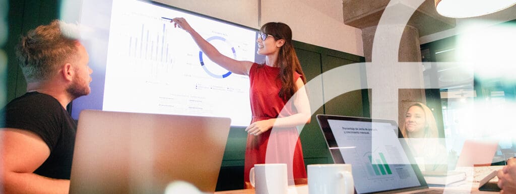 Featured image for article titled "How Copilot is Unleashing New Levels of Creativity" showing a woman presenting something on a big screen.